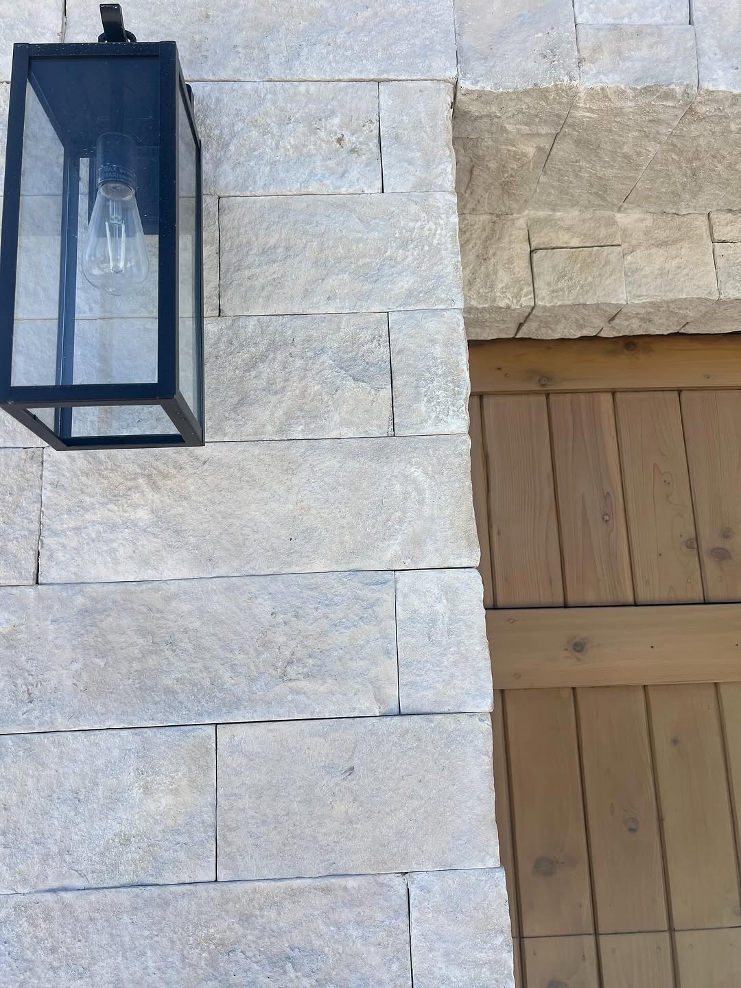 Natural stone veneer wall with a lantern and wood gate